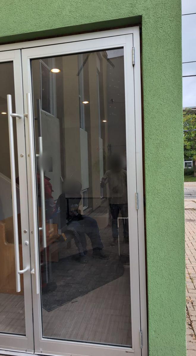 After: the same aluminum entrance door closed, with new clear glass and long pull handles