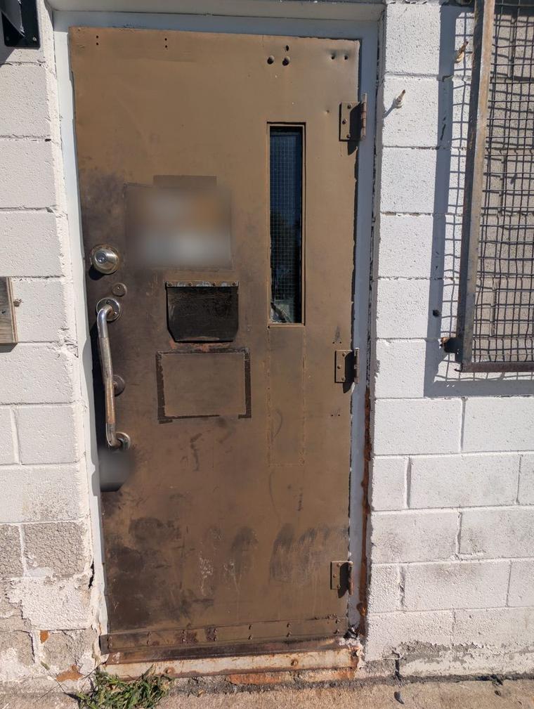 Before: rusted, patched brown steel door on a white block wall, with a grab handle and lockbox