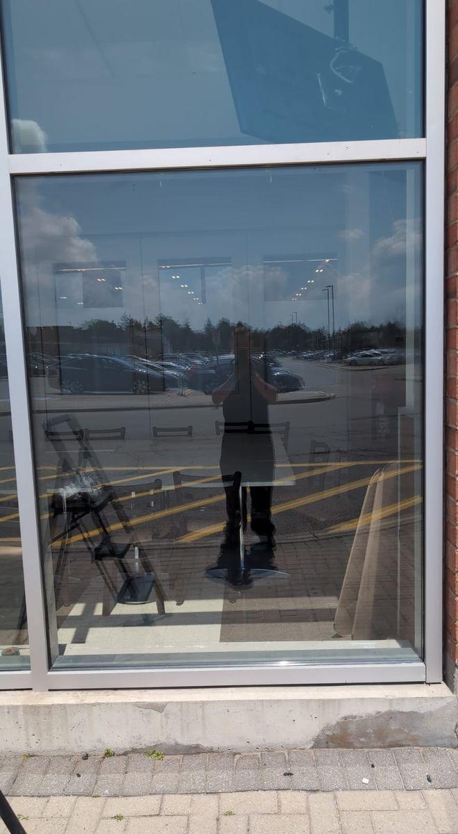 After: the same storefront with a new clear glass panel installed in the aluminum frame